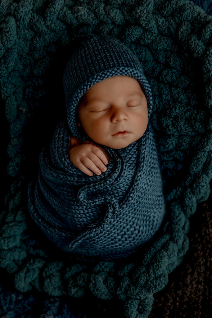 newborn baby boy wrapped in soft blue knit swaddle