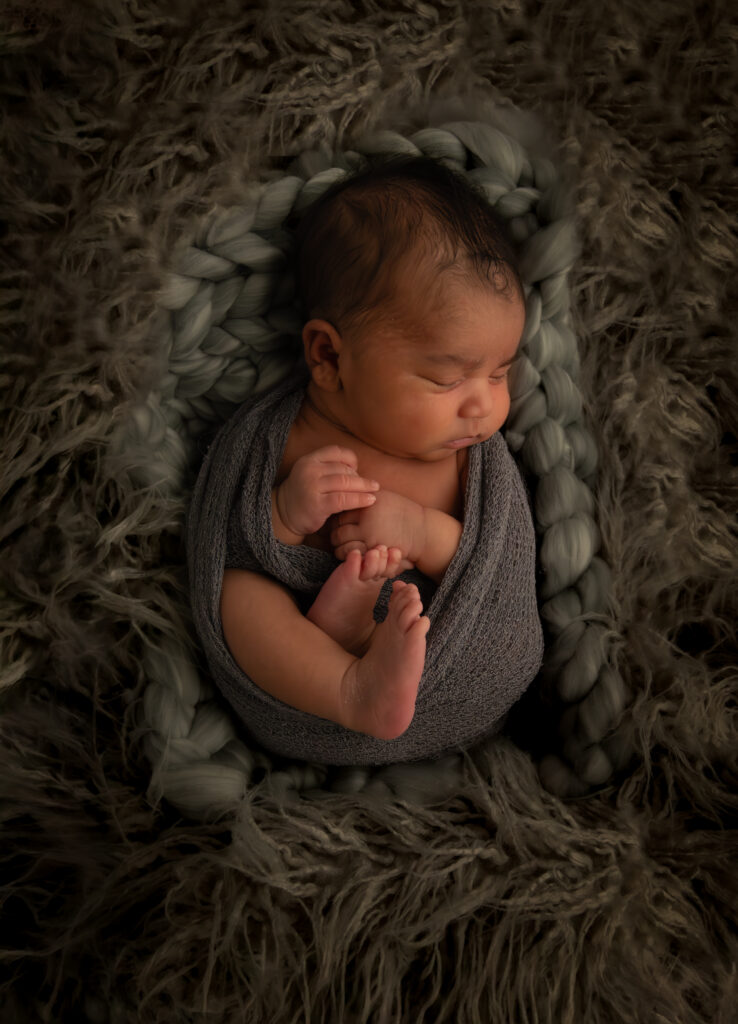 newborn baby boy laying in gray soft blanket