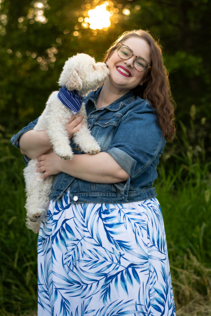 woman smiling while holding dog and warm glow of a sunset