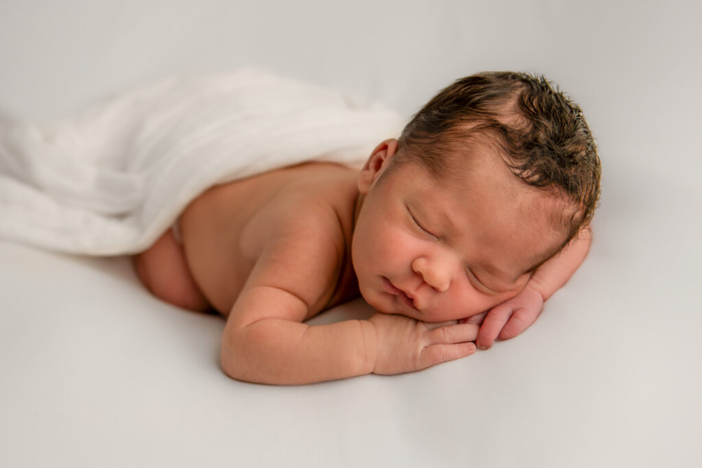 newborn baby boy sleeping on white blanket