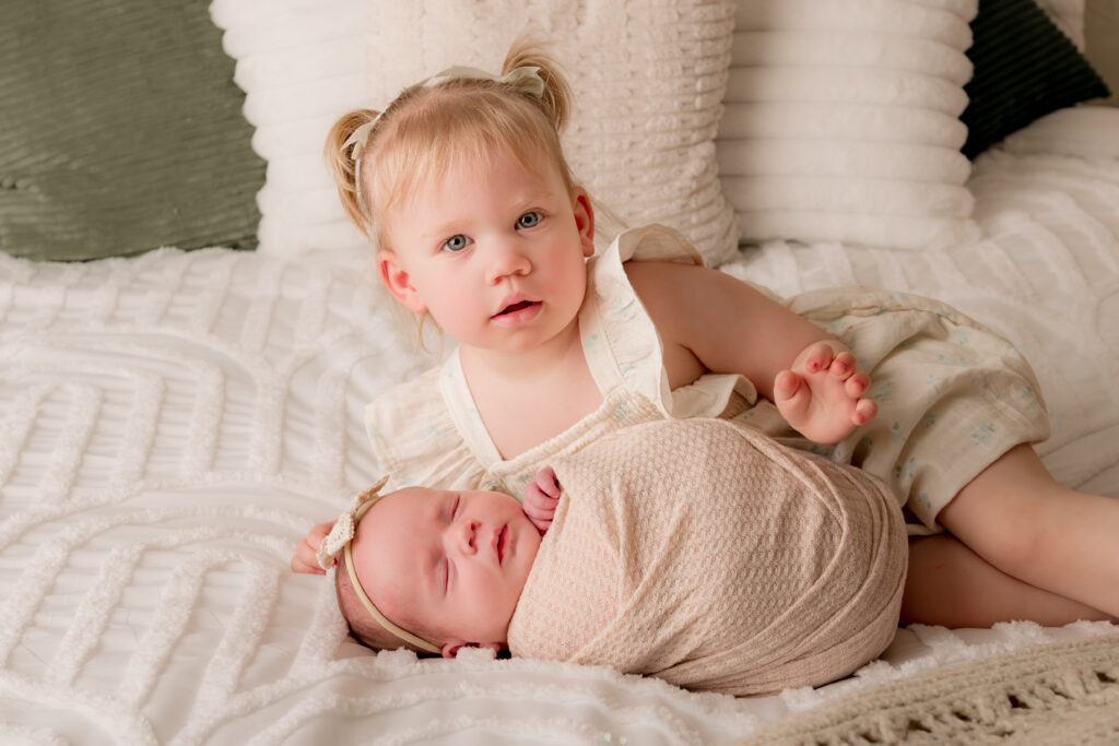 newborn baby girl with sister on soft cozy bed