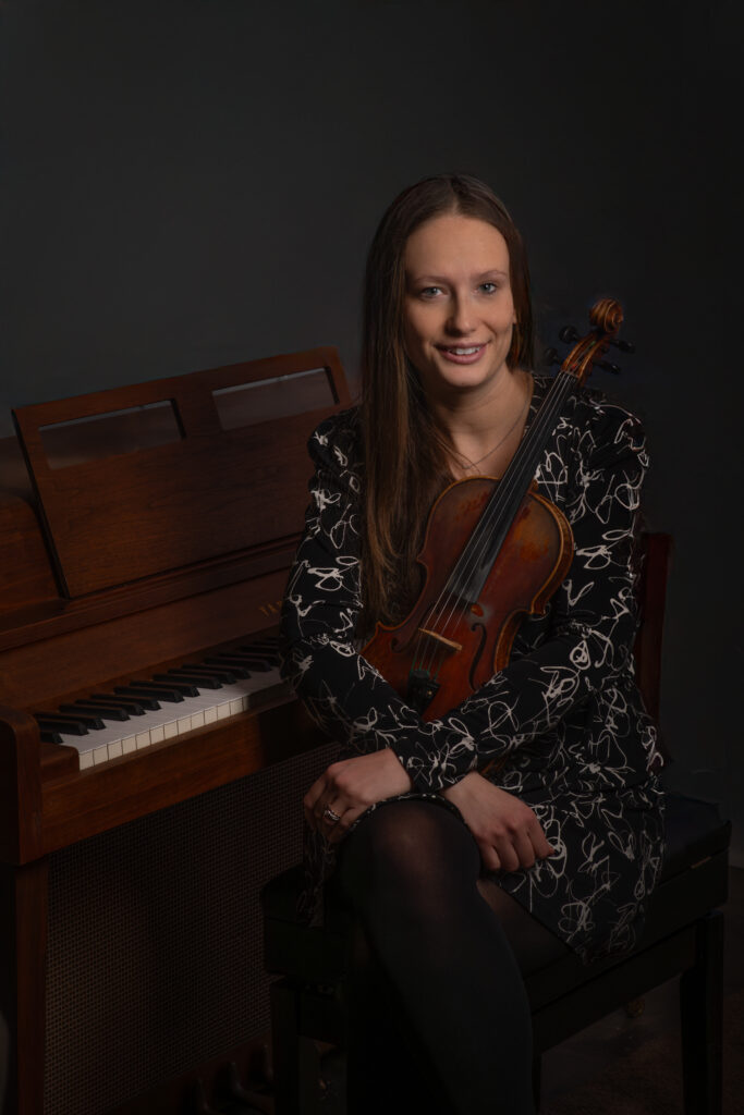 woman seated by piano with violin