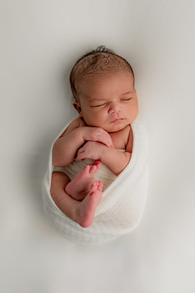 newborn baby boy wrapped in white cloth sleeping