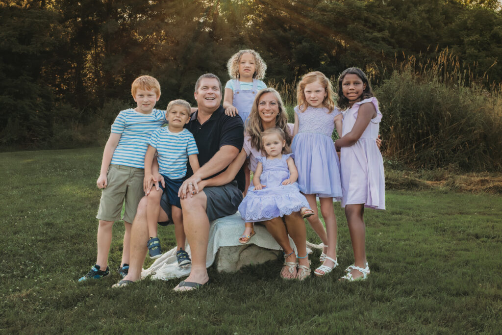 large family in a park posing for picture with sunset behind them