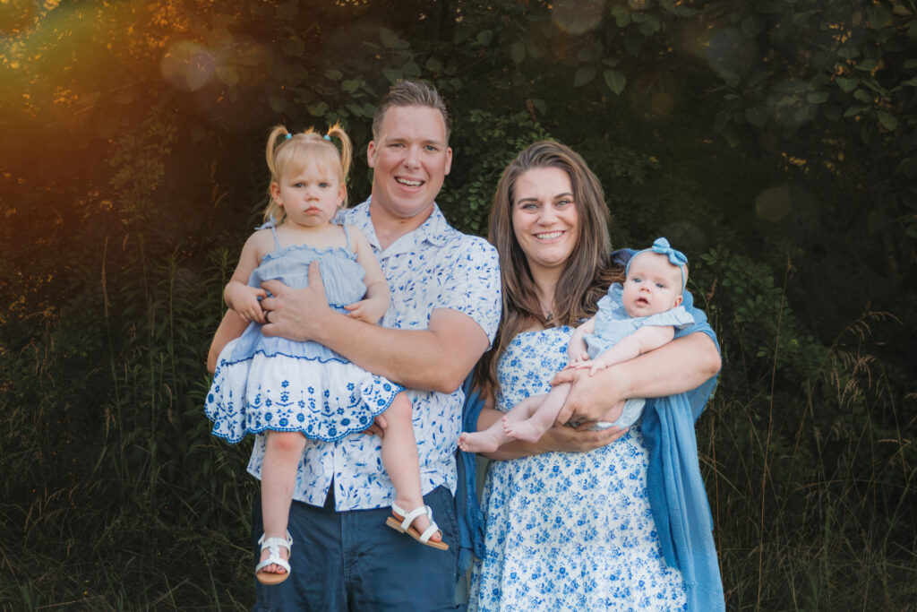 family posing for picture in a park while the sun is setting
