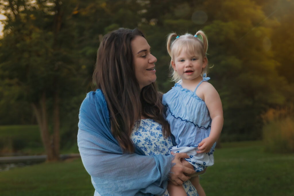 mom and daughter posing for picture in a park at sunset
