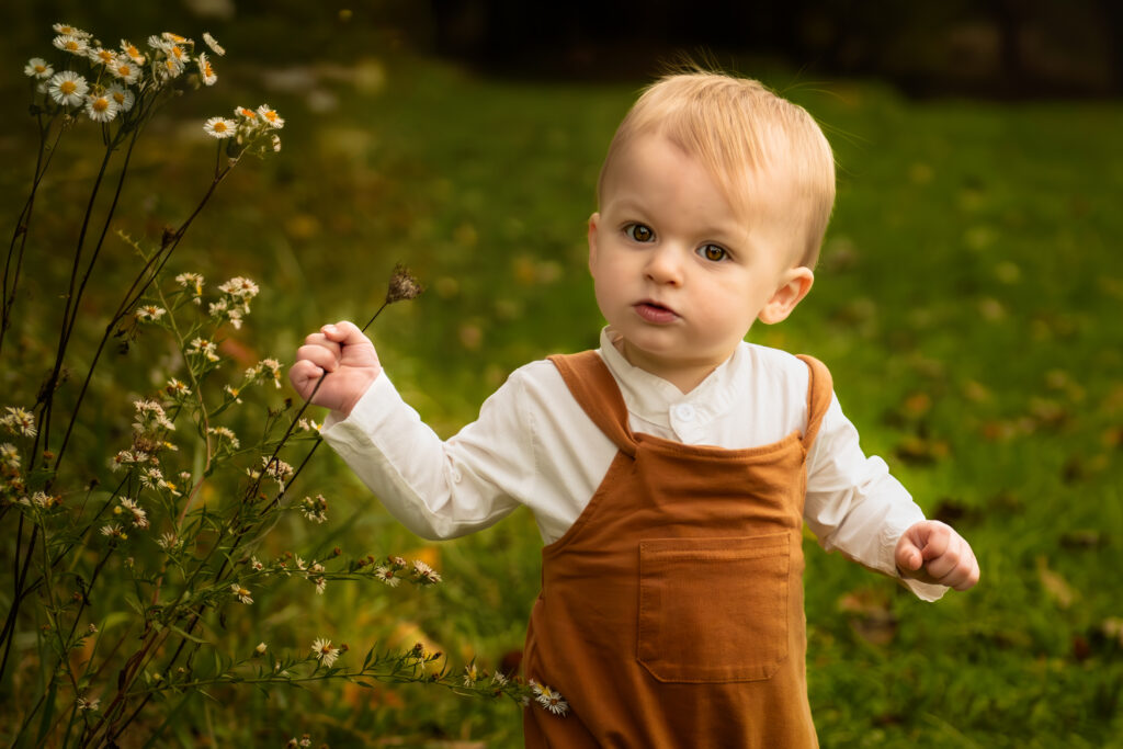 young toddler boy posing by flowers for outdoor picture