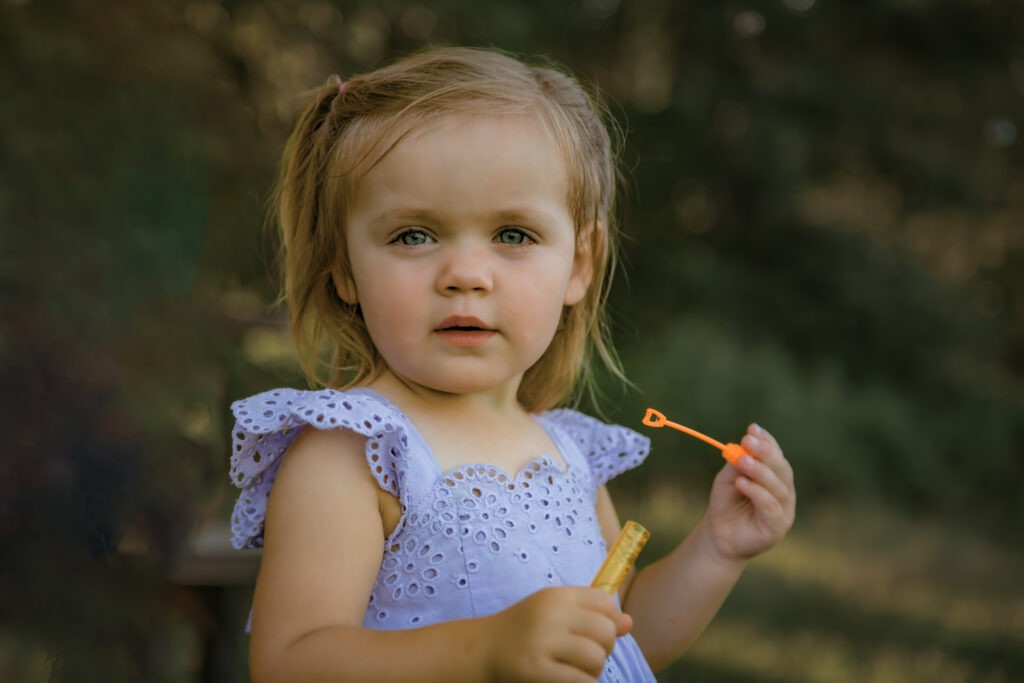 girl blowing bubbles outdoors at sunset family pictures