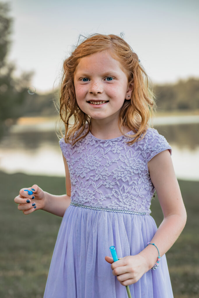 girl smiling at sunset for family pictures outdoors in summer