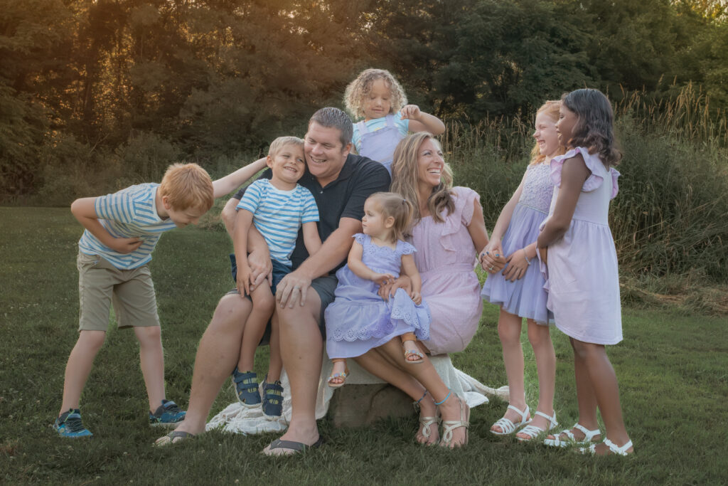 big family laughing outdoors at sunset