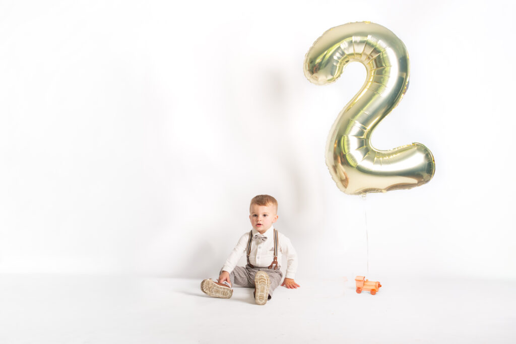 two year old baby boy with train and 2 balloon sitting on floor photography pictures