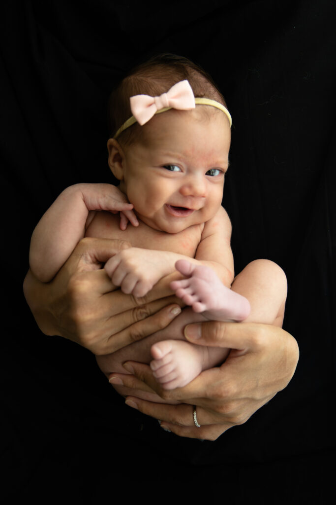 smiling baby held by mom's hands first pictures