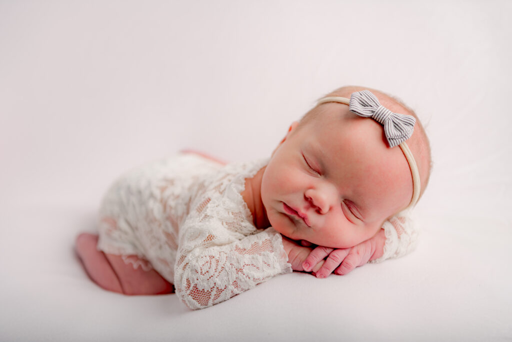 newborn baby with bow sleeping for first pictures