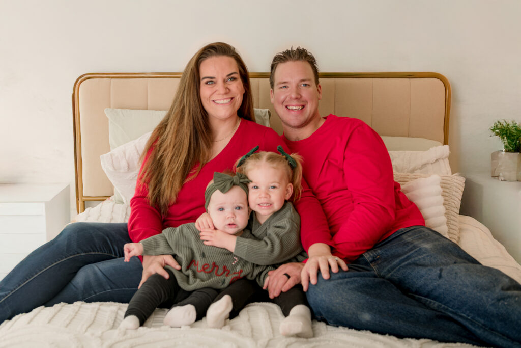 family posed for picture with toddler sibling girls in studio