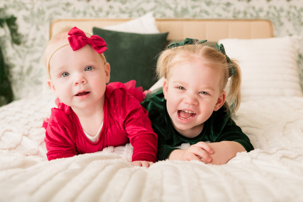 toddler siblings laugh while posing for family picture in studio